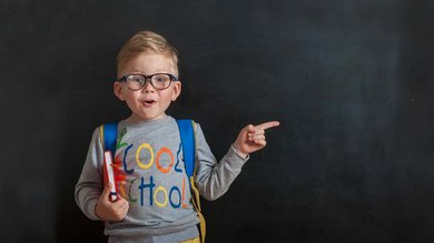 Grundschüler freut sich und zeigt auf eine Tafel